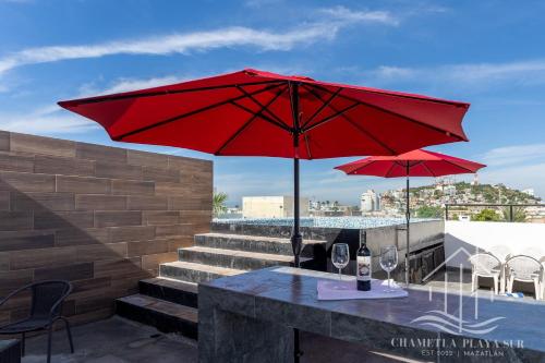 马萨特兰NewComfy~5 Area~Walk 2 Beach~Pool~Views~King Bed的露台上的一张桌子和两把红伞