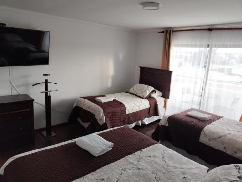 卡尔德拉HOTEL QUINTA ESTACIÓN的一间设有三张床的客房,墙上有一个十字架