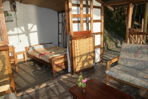 卡巴莱Amasiko Homestay Lake Bunyonyi的客房设有床、沙发和桌子。
