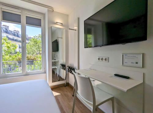 巴黎贝斯特韦斯特巴纳斯峰酒店的客房设有白色桌子和大窗户。