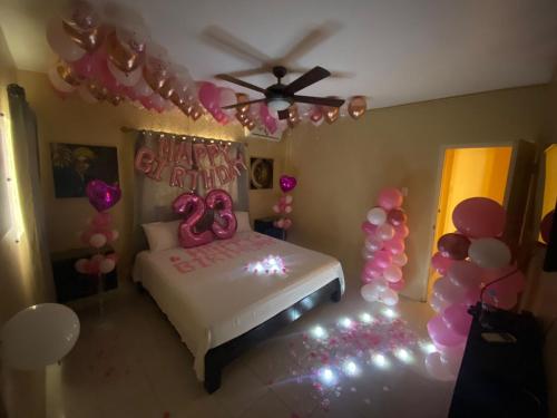 蒙特哥贝Marshan villa的一间卧室配有一张带粉红色气球的床和天花板