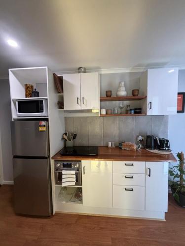 天鹅山Kima Quarters的厨房配有白色橱柜和不锈钢冰箱