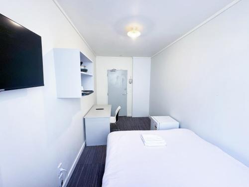 惠灵顿140 Ghuznee Hostel的小房间设有床铺和电视