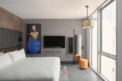 墨尔本The Motley Hotel的一间卧室配有一张床和一台平面电视