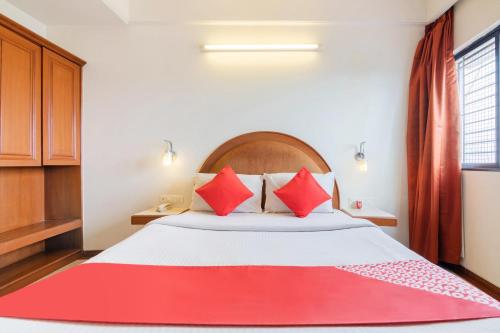 班加罗尔OYO Hotel Sunil Residency的一间卧室配有一张带红色枕头的大床