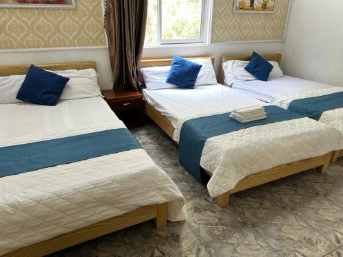 吉婆岛NA NA Homestay的带3张床和蓝色枕头的客房