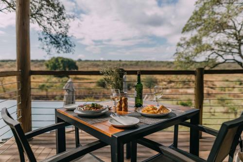 雾观Mdluli Safari Lodge的一张桌子,上面放着两盘食物和一瓶葡萄酒