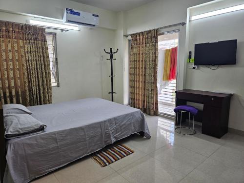 达卡Sweet Rest Dhaka的一间卧室配有一张床、一台电视和一把椅子