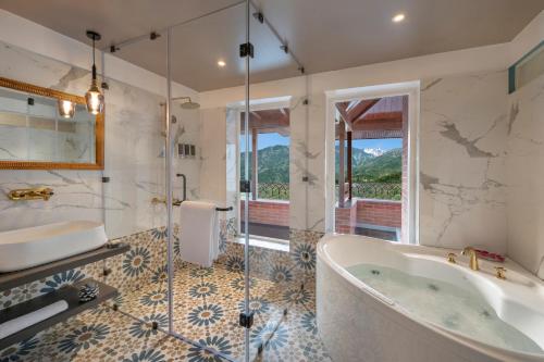 达兰萨拉juSTa Birding Resort & Spa - Best Dhauladhar View Resort的带浴缸和玻璃淋浴间的浴室。
