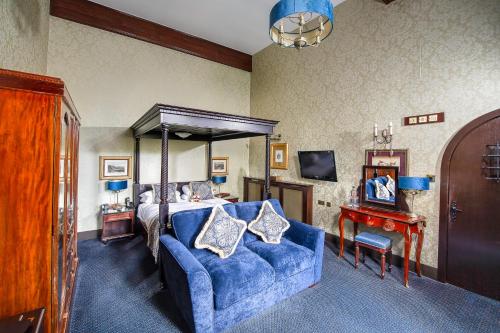 赫克瑟姆兰利城堡酒店的一间卧室配有一张床和一张蓝色的沙发