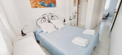 阿尔卡纳尔2 bedrooms apartement at Alcanar 100 m away from the beach with shared pool and furnished terrace的白色卧室配有蓝色的床和白色枕头