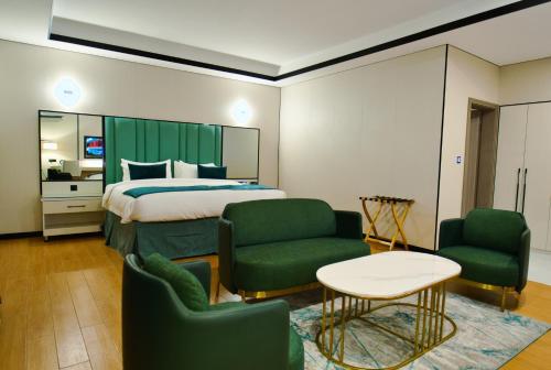 莱基Blu Atlantic Hotel的酒店客房,配有一张床和两张绿色椅子