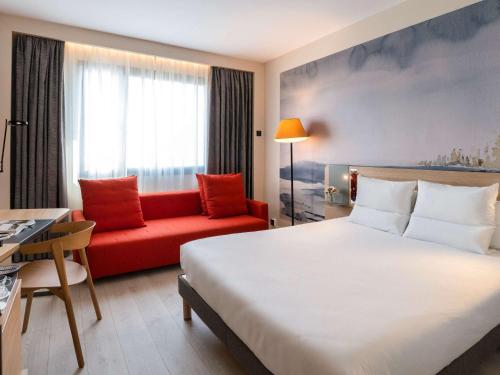 马德里Novotel Madrid City Las Ventas的酒店客房,配有一张床和一张红色的沙发