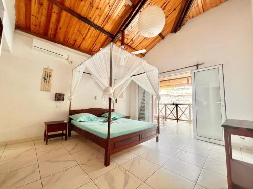 贝岛Résidence Kambana的一间卧室设有一张带木制天花板的天蓬床。