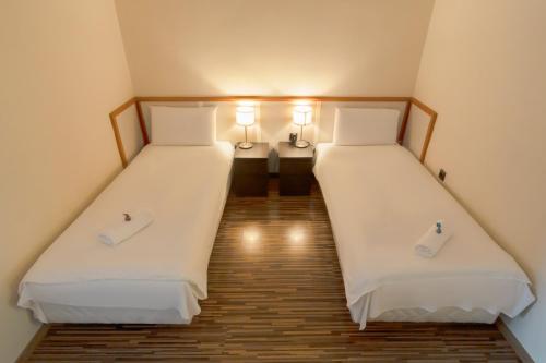 尼赖吉哈佐卡罗纳酒店的小客房内的两张床,配有白色床单