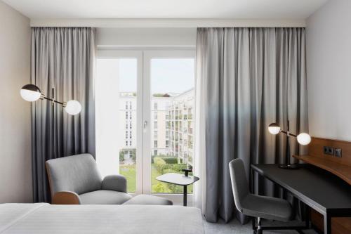 慕尼黑慕尼黑东部万豪酒店的配有一张床、一张书桌和一扇窗户的酒店客房