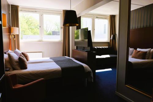 玛丽斯塔德Vänerport Stadshotell i Mariestad的酒店客房,配有两张床和椅子