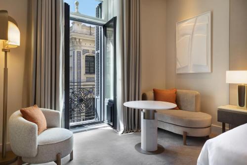 马德里JW Marriott Hotel Madrid的一间设有两把椅子、一张桌子和一个窗户的房间