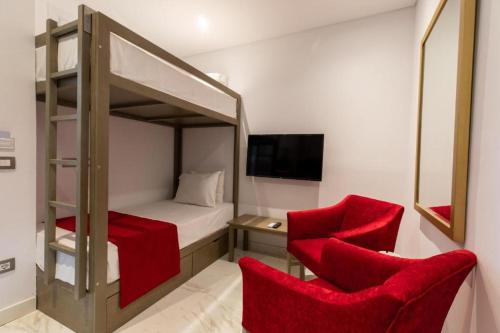 阿莱曼premium sea porto marina suite的一间卧室配有双层床和两张红色椅子