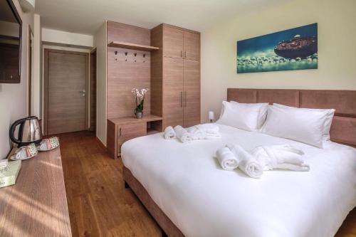 布达佩斯Vitta Hotel Superior的卧室配有带毛巾的大型白色床