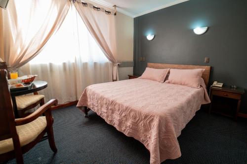 康塞普西翁Hotel Vitali的一间卧室配有一张带粉色毯子的床和窗户。