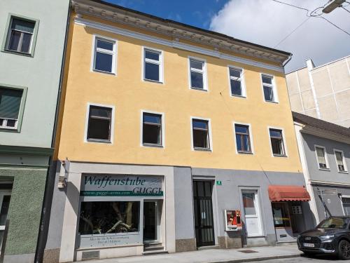 格拉茨格拉茨城市公寓的街上的黄色建筑,有商店