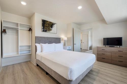 欧文Soka Suites Dallas - Las Colinas的一间卧室配有一张大床和一台平面电视