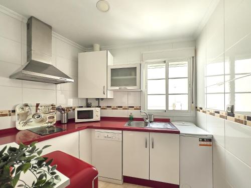 加的斯Studio Novena Little Apartments的厨房配有白色橱柜和红色台面
