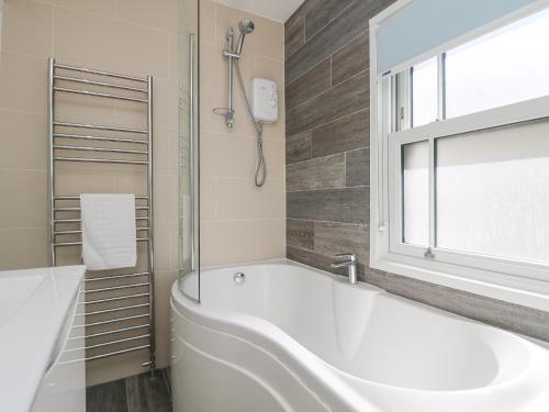 纽林Rose Villa的带窗户的浴室内的白色浴缸