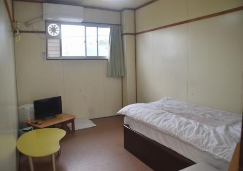 德之岛Guest House Minatoya Tokunoshima - Vacation STAY 01034v的一间卧室配有一张床、一张书桌和一个窗户。