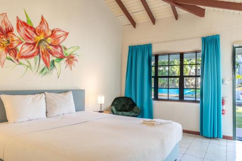 奥拉涅斯塔德Talk of the Town Inn & Suites - St Eustatius的卧室配有一张床,墙上挂有花卉画