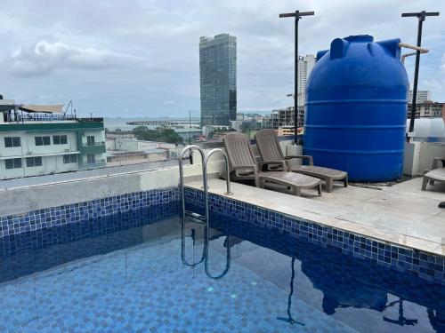巴拿马城Hotel HSR的一个带两把椅子的游泳池,一个蓝色的大桶