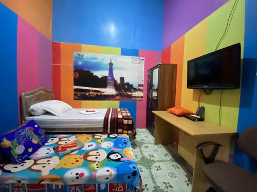 科贾扬Pelemkecut Double-Degree Syariah Accommodation的色彩缤纷的客房设有一张床和一台电视机