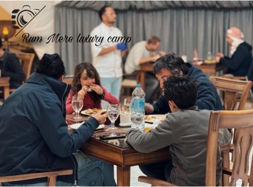 瓦迪拉姆Rum Mere luxury camp的一群坐在餐桌上吃食物的人