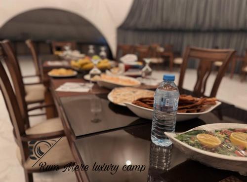瓦迪拉姆Rum Mere luxury camp的餐桌,带食物盘和一瓶水