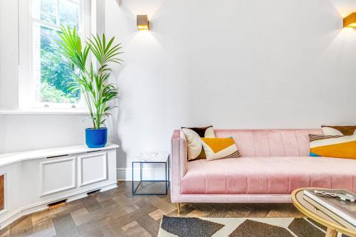 伦敦Flat in Chelsea的客厅配有粉色的沙发和盆栽植物