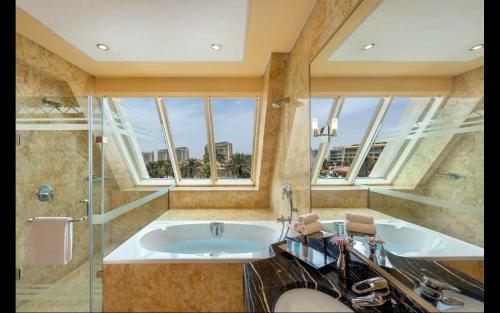 阿布扎比Al Raha Beach Hotel - Gulf View Room DBL - UAE的带浴缸和大窗户的大浴室