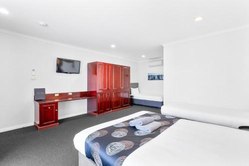 林肯港喜尔顿汽车旅馆的一间卧室配有一张床、一张书桌和一台电视。