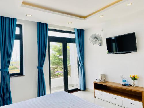 芽庄Thanh Hien villa的一间卧室配有蓝色窗帘和平面电视