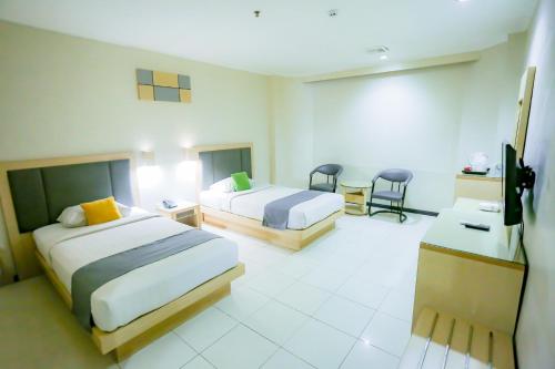 坤甸坤甸梅尔帕提酒店的酒店客房,配有两张床和两把椅子
