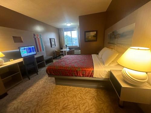 加迪纳市Hotel Pacific Garden的酒店客房配有一张床、一张书桌和一台电视。