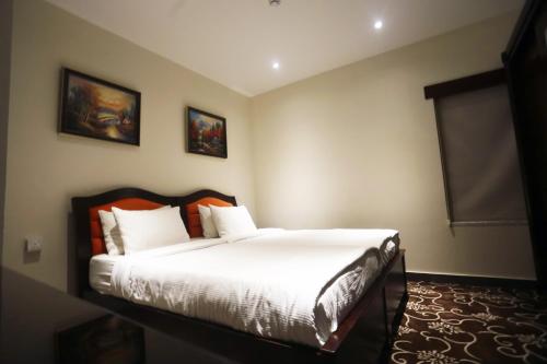 安曼内洛夫套房酒店的一间卧室配有带白色床单和橙色枕头的床。