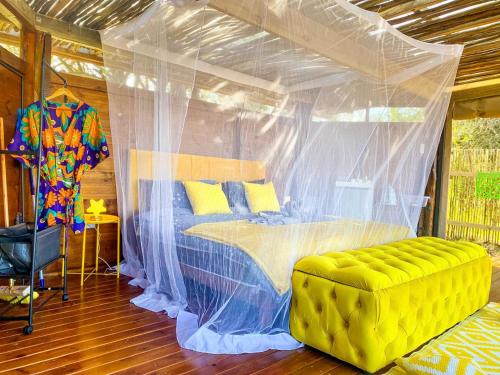 赫卢赫卢韦Hluhluwe Bush Camp Glamping Village的一间卧室设有天蓬床和黄色沙发。
