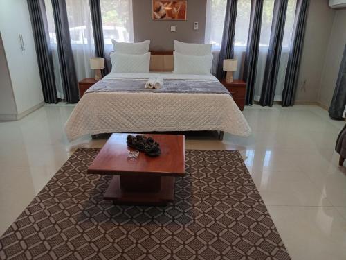 卢萨卡Nangoma Safari Lodge Lusaka的一间卧室配有一张大床和一张桌子