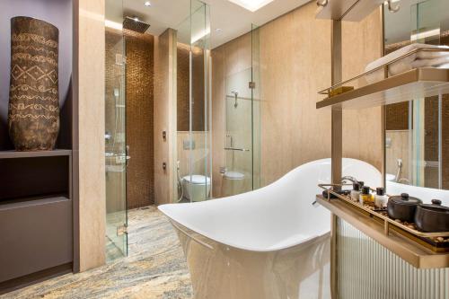 TemonMORAZEN Yogyakarta的浴室配有白色浴缸和玻璃淋浴间。