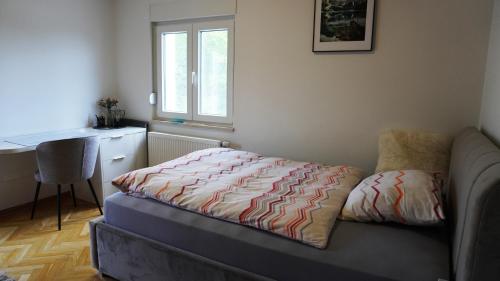 Široki BrijegApartment Zona的一间卧室配有一张床、一张书桌和一个窗户。