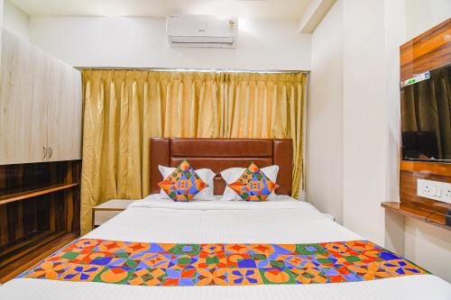 kolkataFabHotel The Luxurie International的一间卧室配有一张带五颜六色棉被的床