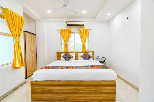 加尔各答FabHotel Grand Hazra Inn的一间卧室配有一张带黄色窗帘的大床