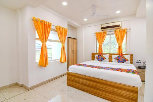 加尔各答FabHotel Grand Hazra Inn的一间卧室配有带橙色窗帘的大床