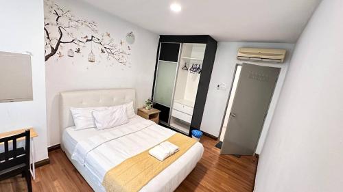 吉隆坡Taragon Apartment - KL的卧室配有白色的床,墙上挂着一棵树壁画